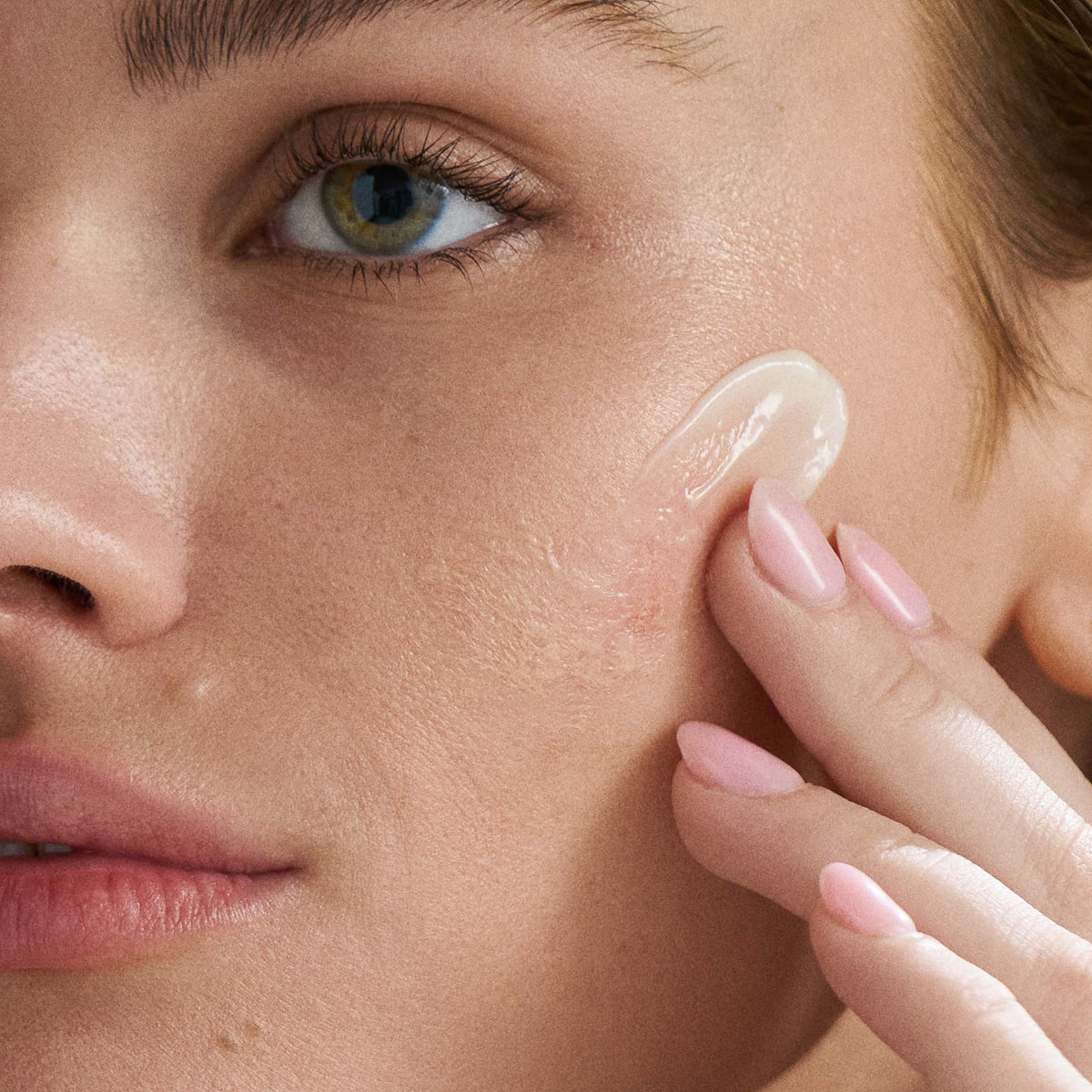 Close-up of a woman applying cream to her face 